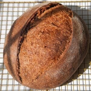 sourdough brown bread on a cooling rack
