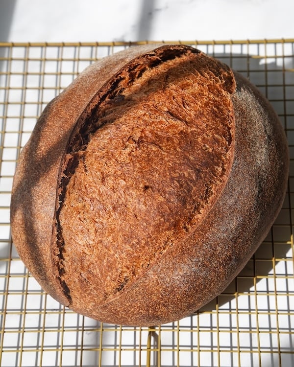 sourdough brown bread on a cooling rack