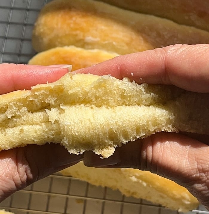 hands squishing a hot dog bun, showing how soft it is