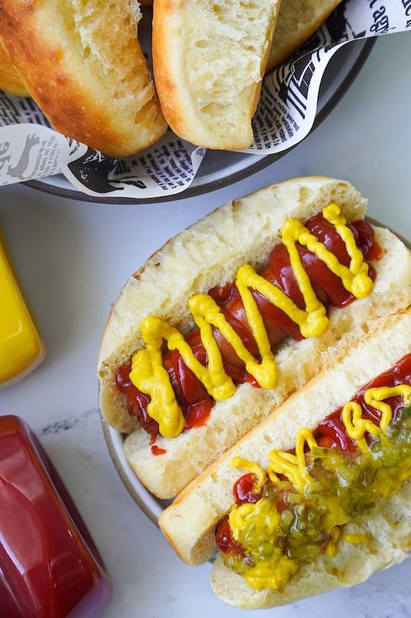 top down view of hawaiian roll hot dog buns with hot dogs and all fixings