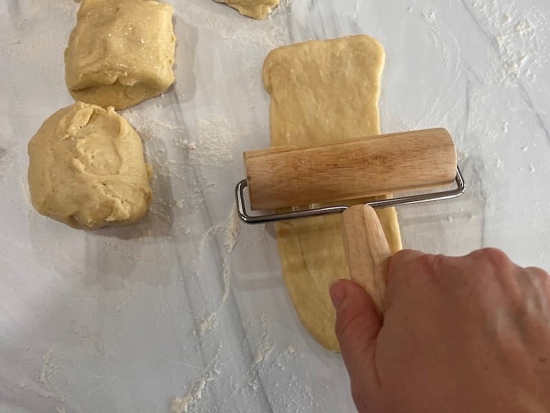 using a small rolling pin to roll out hot dog bun dough