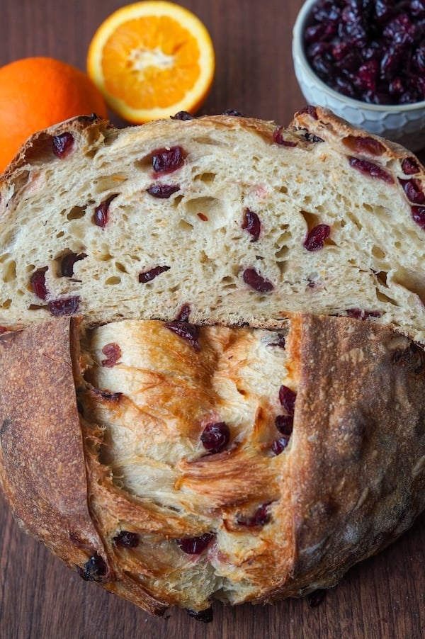 A close look at the cranberries and orange zest flecks inside the halved loaf
