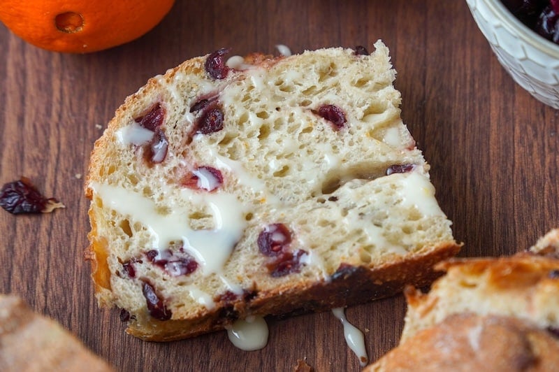orange glaze on a slice of orange cranberry sourdough bread